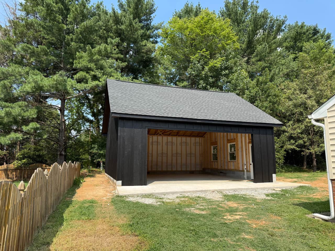 A finished detached garage with black board-and-batten siding and a new shingle roof, built by YKY Martínez Remodeling