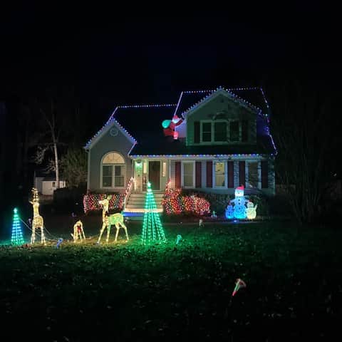 Home and front yard illuminated with colorful Christmas lights and holiday figures