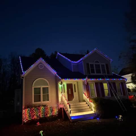 Two-storey home outlined with colorful Christmas lights around the roof and porch